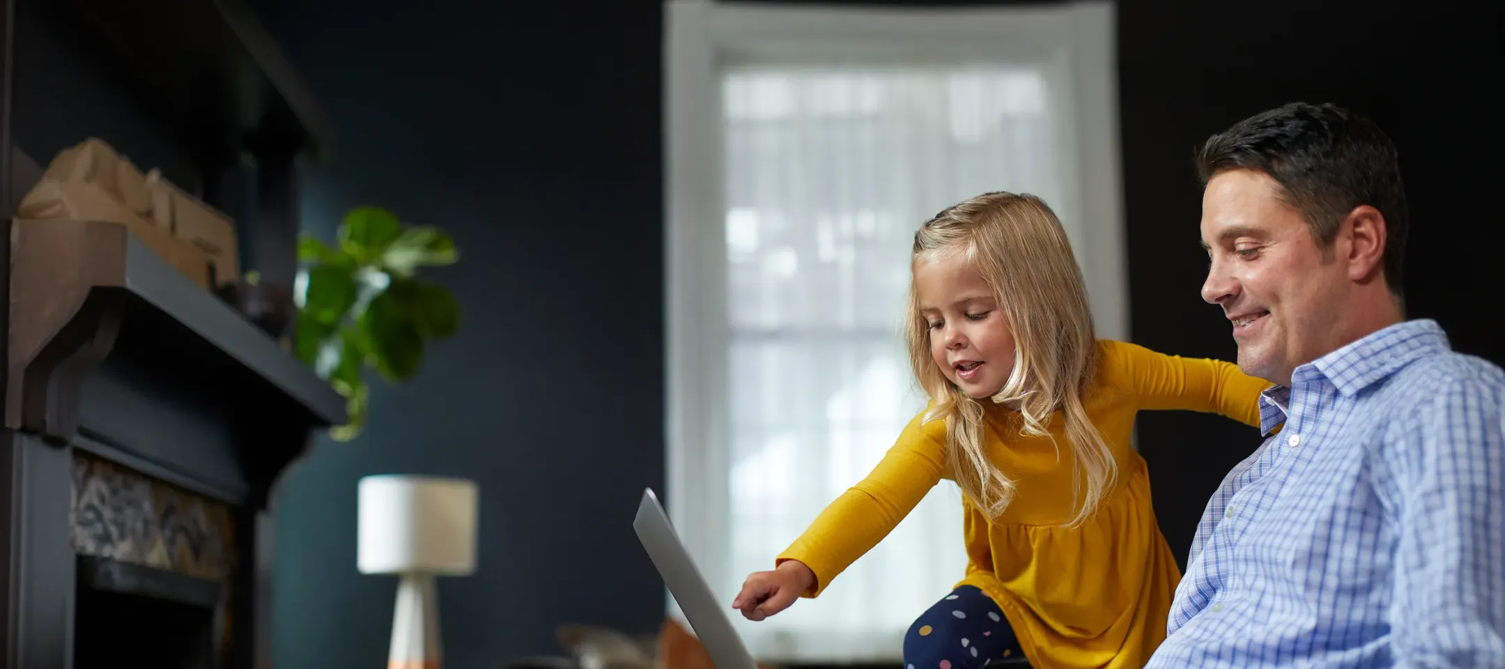 WTC Communications - Happy father and daughter enjoying fast, reliable home internet on a laptop.