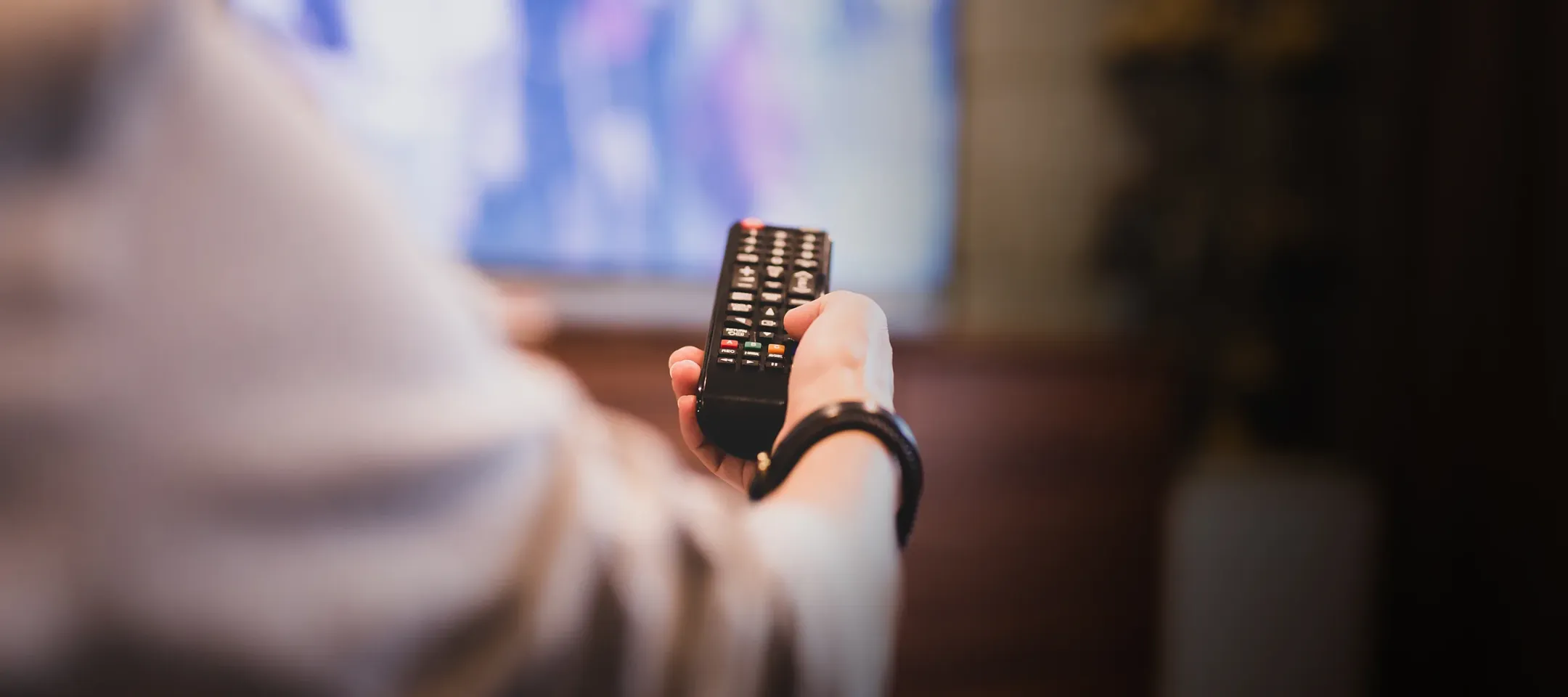 Relaxed person using TV remote watching NHL on WTC TV service channels
