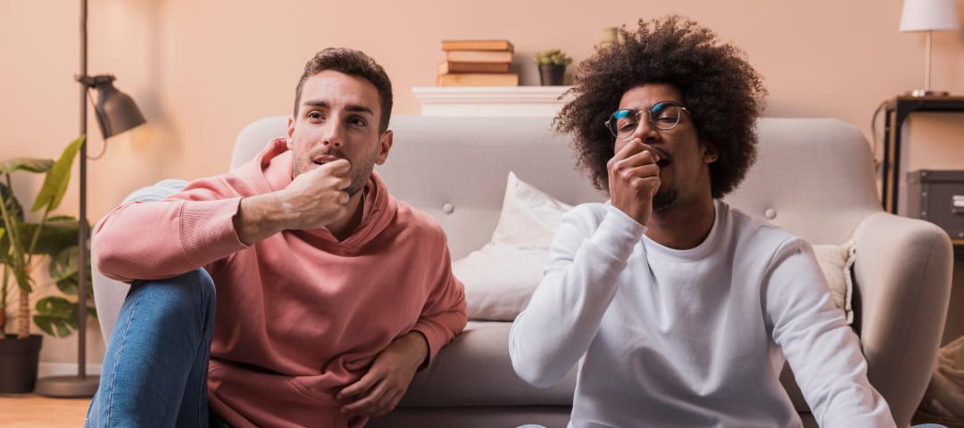 Photo of two men sitting in front of a couch eating popcorn