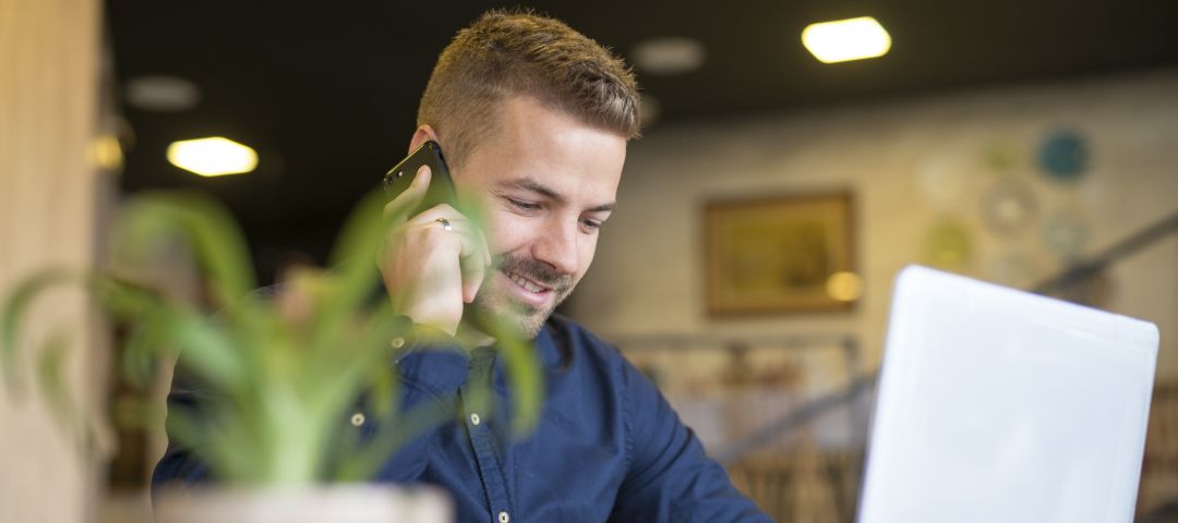 Young Man talking on Phone with Laptop