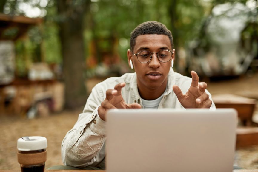 Man talking with his hands outside on zoom call meeting with his laptop.