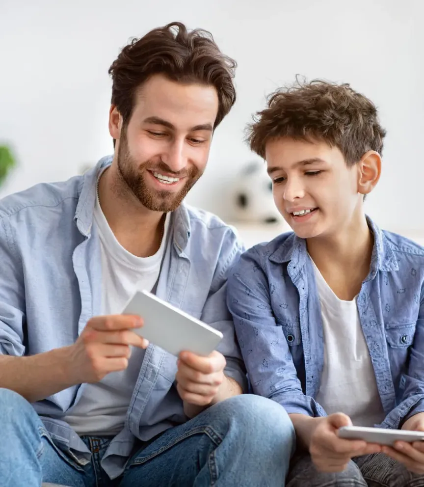 WTC Communications Westport - Father and son happily connecting with their phones at home, enjoying reliable internet.