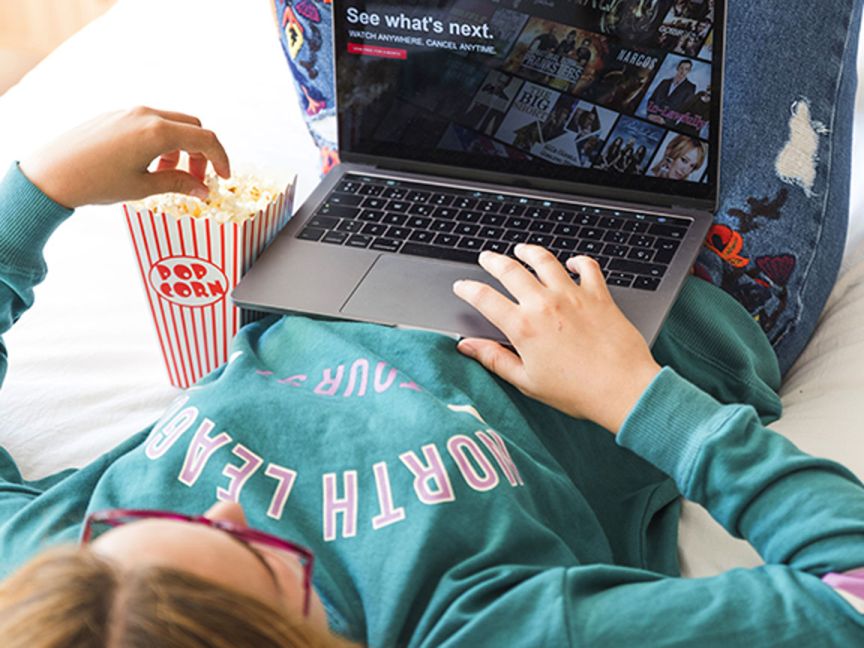 A person eats popcorn while using a notebook computer