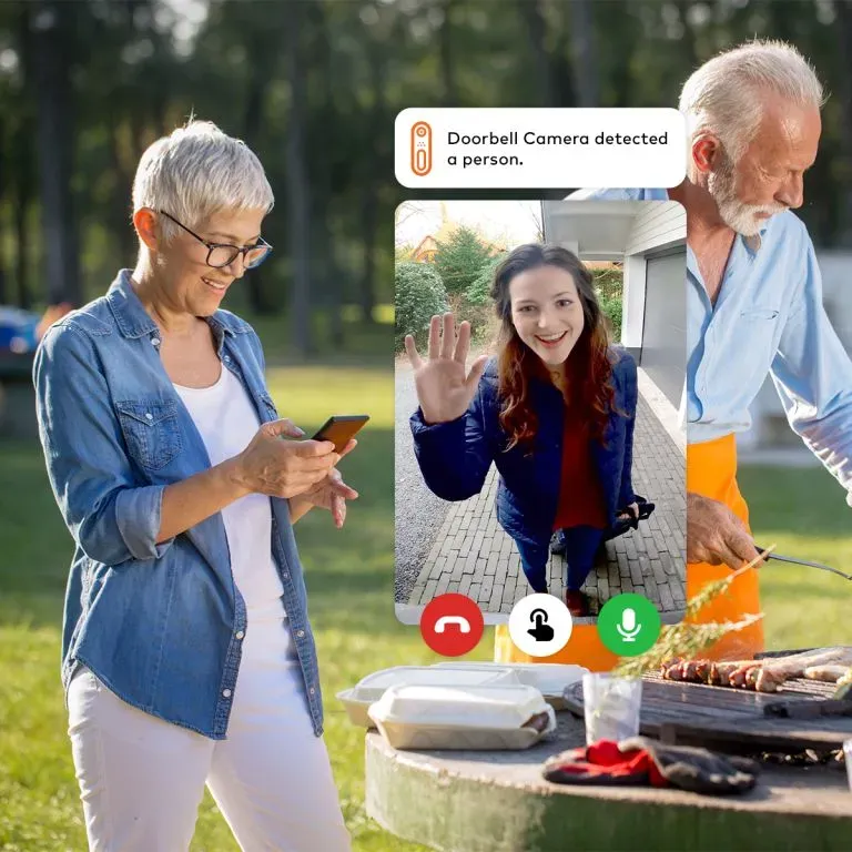WTC Communications Kingston - Couple using smart home doorbell camera to video call a visitor while barbecuing.