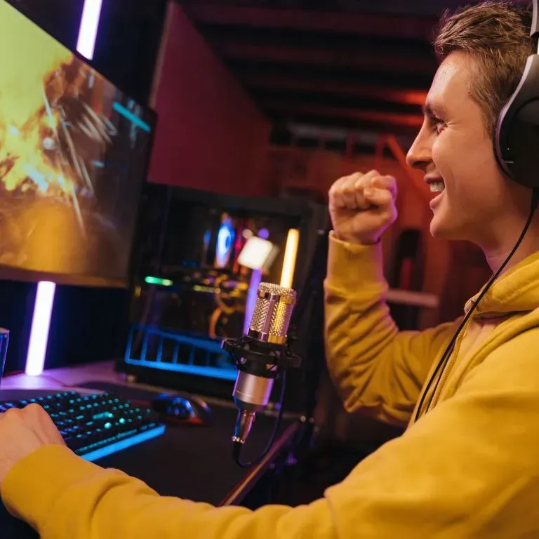 WTC Communications - Excited gamer celebrating a win on a powerful PC, enjoying high-speed fibre internet in Kingston.