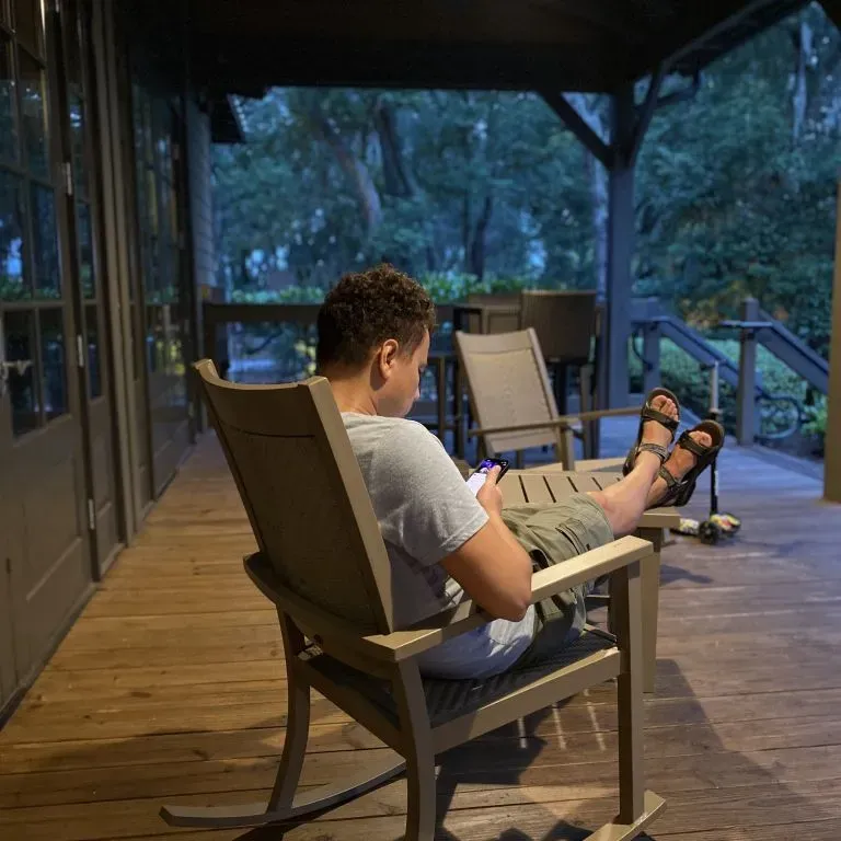 WTC Communications Perth - Person relaxing and gaming on his phone on a porch, enjoying seamless connectivity.